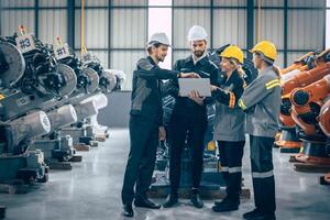 Group of engineer team stand talking together. Industry engineering teamwork people discussion. Robot arm design assembly plant meeting with laptop computer for exchange knowledge. photo