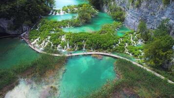 Hiking trail over crystal clear emerald water of lake. Path for tourists in mountain national park with waterfalls. video