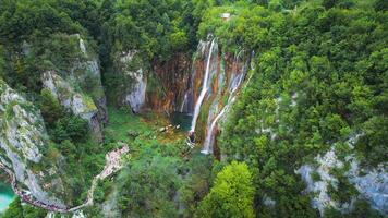 naturskön hög vattenfall cascading över frodig grön klippa i tät skog. berg ström med klar vatten. video