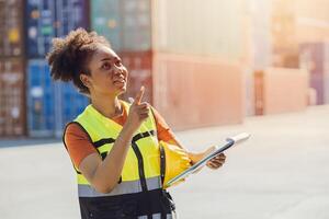 African woman cargo logistics industry staff worker happy working in port shipyard check containers photo