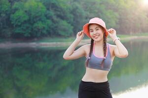 sport healthy Asian woman standing outdoor happy smile cute with forest lake background photo