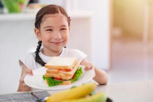 asiático linda hija contento disfrutar comiendo sano comida Mañana comida vegetal ensalada emparedado foto