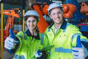 happy engineer team portrait thumbs up enjoy working together in modern metal factory with robotic arm photo