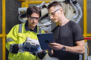 ingeniero equipo trabajando programa robot soldadura brazo en automatizado fábrica. robótico especialistas hablando juntos en máquina industria fabricación foto