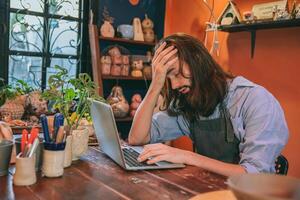 artista trabajando a hogar estudio No cliente contacto negocio fallar abajo. hombre dolor de cabeza cansado exhausto. foto