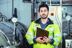 Hispanic smart confident engineer male service worker in factory portrait in boiler water pipe room. photo