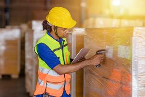 indio trabajador en logística industria trabajando inventario administración sistema utilizando código de barras lector y tableta computadora foto