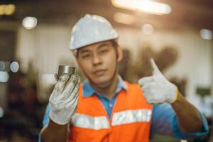 engineer male worker showing best metal part for good quality steel lathe work production photo