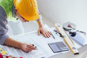 Architect Engineer Builder, Building Designer working with floorplan at Construction Site. photo