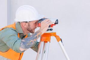 ingeniero constructor trabajando con auto nivel cámara Mira objetivo arrasamiento encuesta construcción edificio piso foto