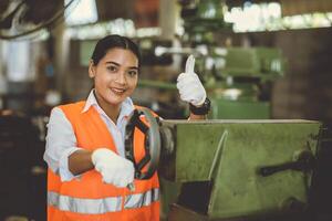 portrait happy woman worker working in heavy industry metal factory Asian smiling thumbs up photo