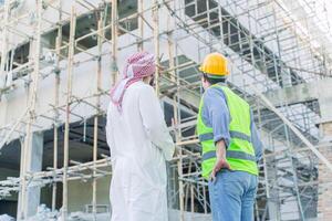 engineer standing with arub property investor looking under construction building for new properties  projects in middle east country photo