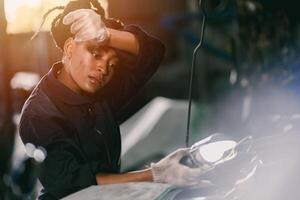 african woman worker hard working tired sweat for mechanic girl engine check garage photo