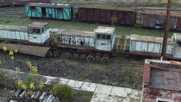 aéreo ver de antiguo oxidado locomotoras y vagones de un estrecho calibre ferrocarril. abandonado ferrocarril deposito. 4k video