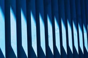 Beautiful wooden blue slats. A streak of sunlight on a wooden fence. Bright abstract background. Element of finishing the facade of the building. photo