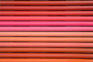 A set of Colored pencils lying in a beautiful gradient transition from yellow to pink and red, brown and purple hues. Abstract background. photo