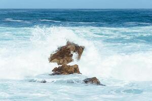 White waves hitting rocks on the ocean shore photo