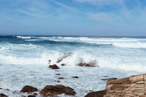 White waves hitting rocks on the ocean shore photo