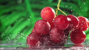 Red grapes fall with splashes on a wet table. Filmed on a high-speed camera at 1000 fps. High quality FullHD footage video