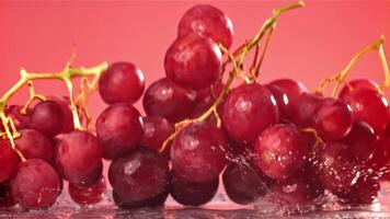 Red grapes fall with splashes on a wet table. Filmed on a high-speed camera at 1000 fps. High quality FullHD footage video