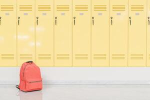 Red Backpack in Front of Yellow School Lockers, Education Concept. photo