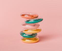 Stack of Colorful Pool Rings on Pastel Pink Background photo