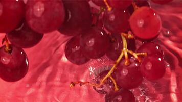 Red grapes fall with splashes into the water. Top view. Filmed on a high-speed camera at 1000 fps. High quality FullHD footage video