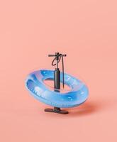 Inflatable Ring with Air Pump on Pastel Pink Background photo