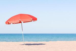 Solitary Red Beach Umbrella on Sandy Shore with Ocean Horizon photo