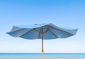 elegante azul playa paraguas de cerca con Oceano antecedentes foto