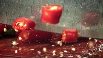 The knife cuts the chili pepper with a splash of water. Filmed on a high-speed camera at 1000 fps. High quality FullHD footage video