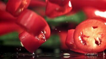 Sliced chunks of chili pepper falling on a black background. Filmed on a high-speed camera at 1000 fps. High quality FullHD footage video