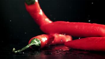 Chili paprika's vallen Aan een nat zwart tafel. gefilmd Aan een hoge snelheid camera Bij 1000 fps. hoog kwaliteit full HD beeldmateriaal video