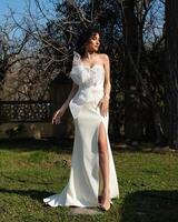 A woman in a white dress stands in front of a house. photo