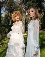 Two women in a white wedding dress stand in a park photo