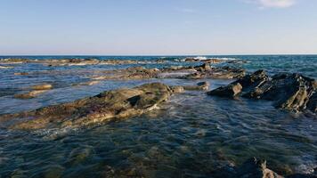 calme vagues frappe le rochers sur le rive video