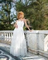 A woman in a white dress stands in front of a house. photo