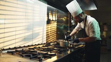 Young professional chef in kitchen while preparing gourmet dishes with a pot video