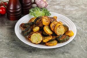 Roasted young zucchini in the plate photo