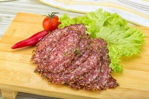 Sliced salami over board photo