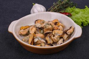 Pickled mussels in the bowl served pepper, garlic and salad photo