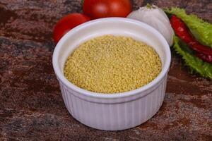 Raw couscous in the bowl served salad leaves, tomato and pepper photo