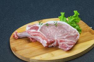 Raw pork bone steak over wooden photo