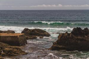 The waves fighting about deserted rocky coast of Atlantic ocean, Portugal photo