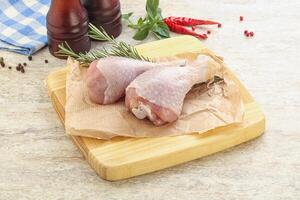 Raw chicken leg over board photo