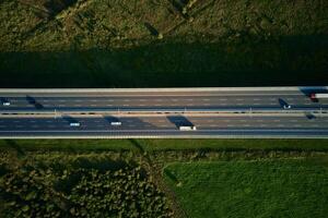 Cars driving on highway road near forest trees, top view photo