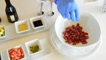 mãos do profissional chefe de cozinha adicionando ingredientes para vermelho ou picado atum peixe video