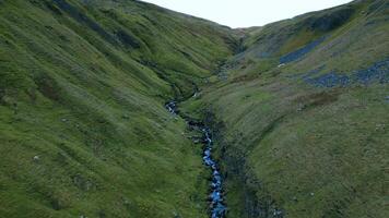 Serene aerial view of a meandering stream flowing through a lush green mountain valley. video