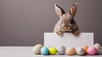 AI generated Easter bunny holding blank white card and painted easter eggs decorations for spring celebration photo