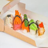 caja lleno con Sushi y vegetales en mesa foto